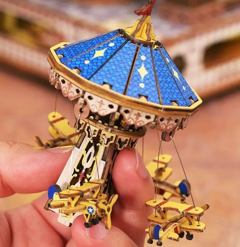 miniature model of a wooden carousel with rotating little planes held in hand