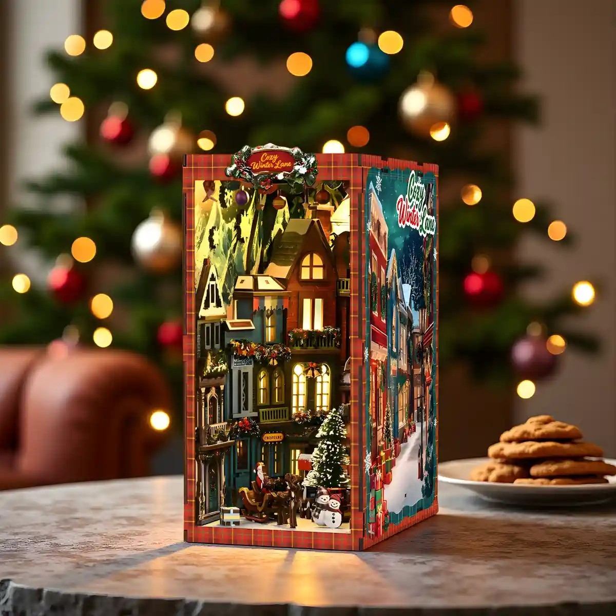 Christmas-themed book nook with a festive village design on a table in front of a decorated tree.