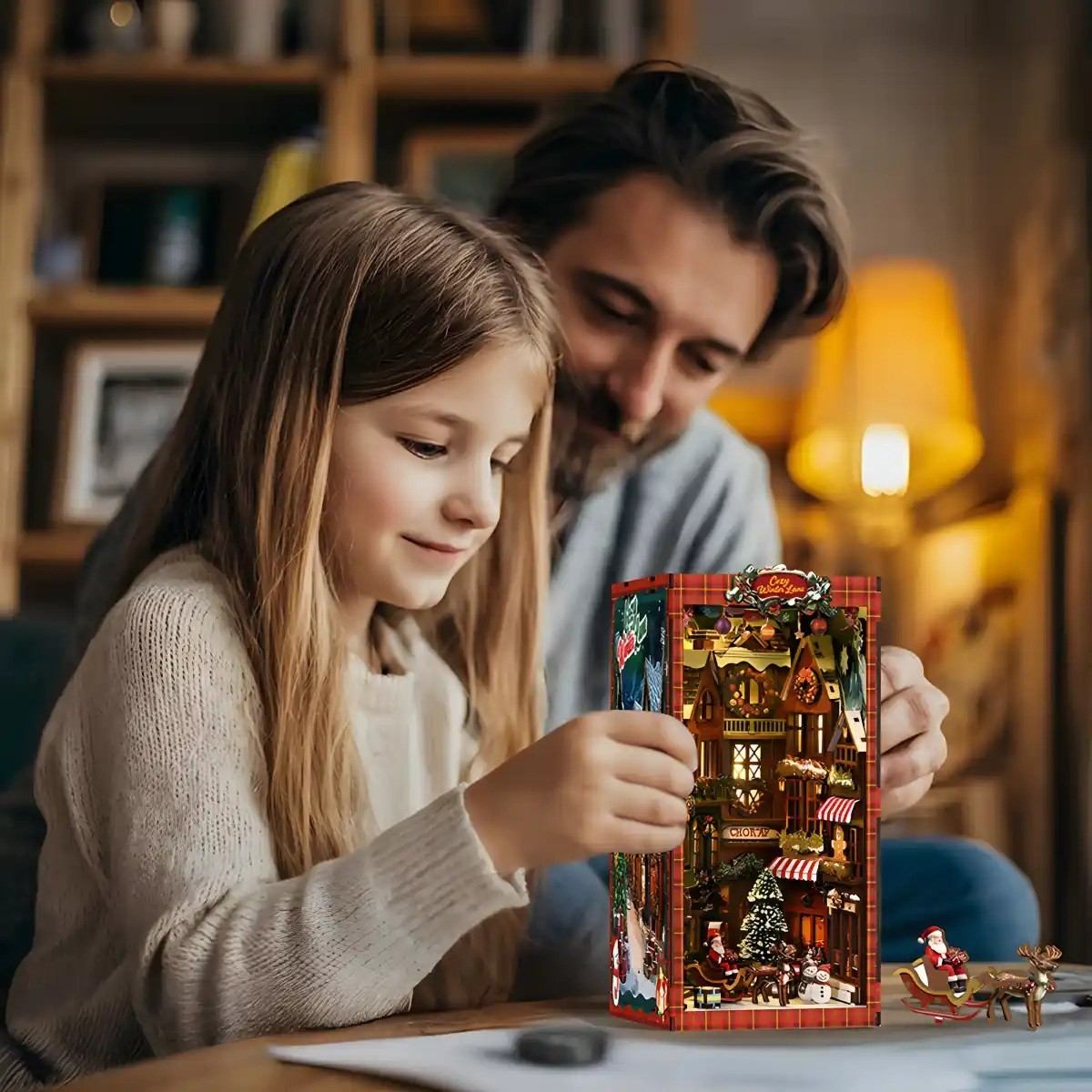 Man and young girl looking at a small, detailed book nook model of a Christmas street.