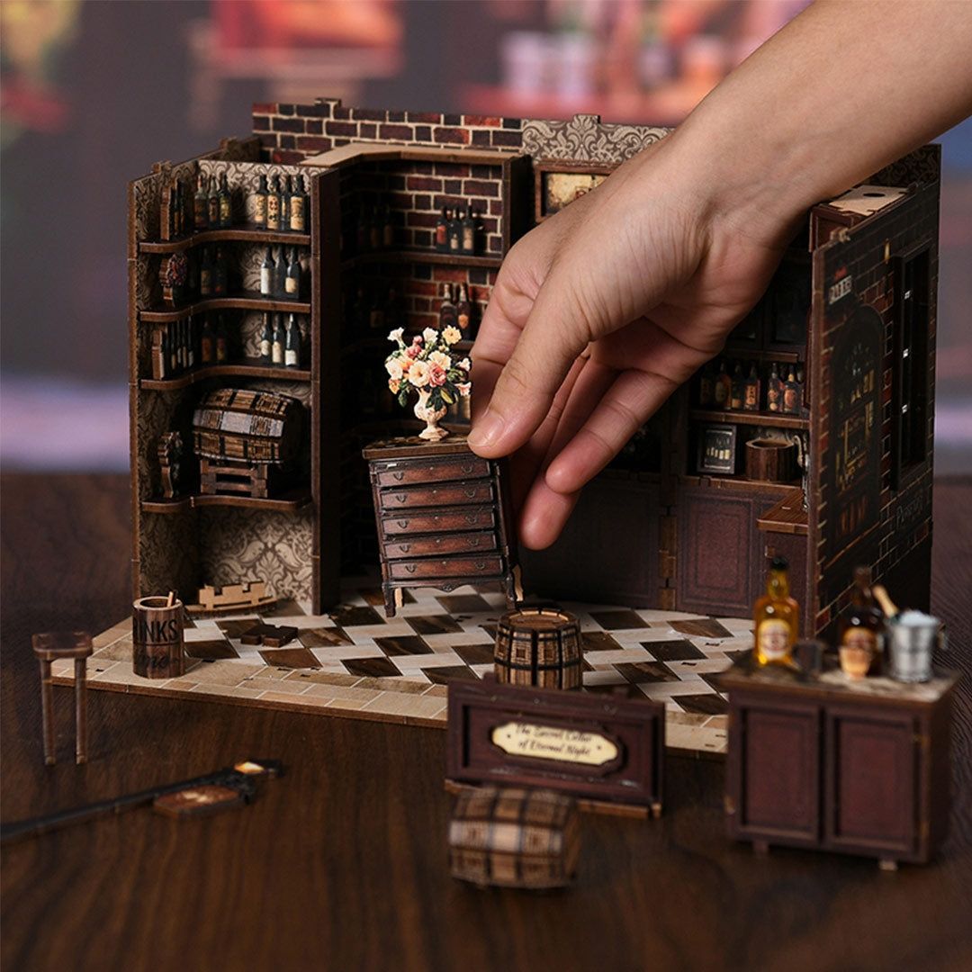 Hand interacting with a miniature bar setup on a wooden surface.
