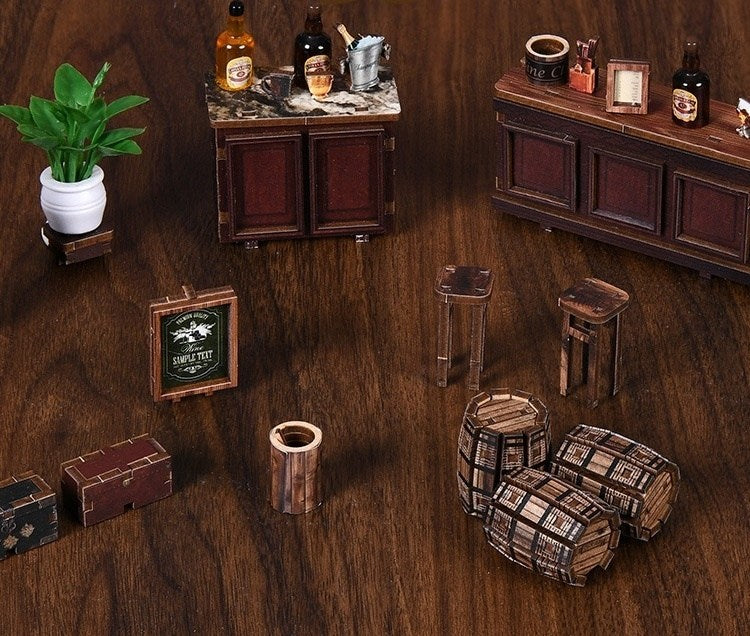 Miniature wooden furniture and props arranged on a wooden floor, resembling a rustic setting.