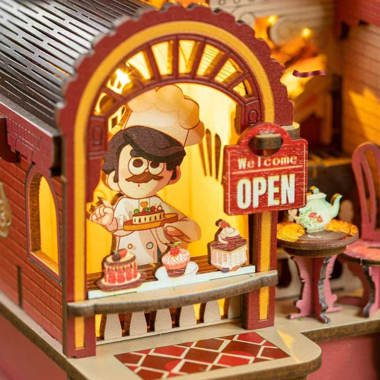 Wooden toy bakery with a chef character and 'Open' sign, lit from within.