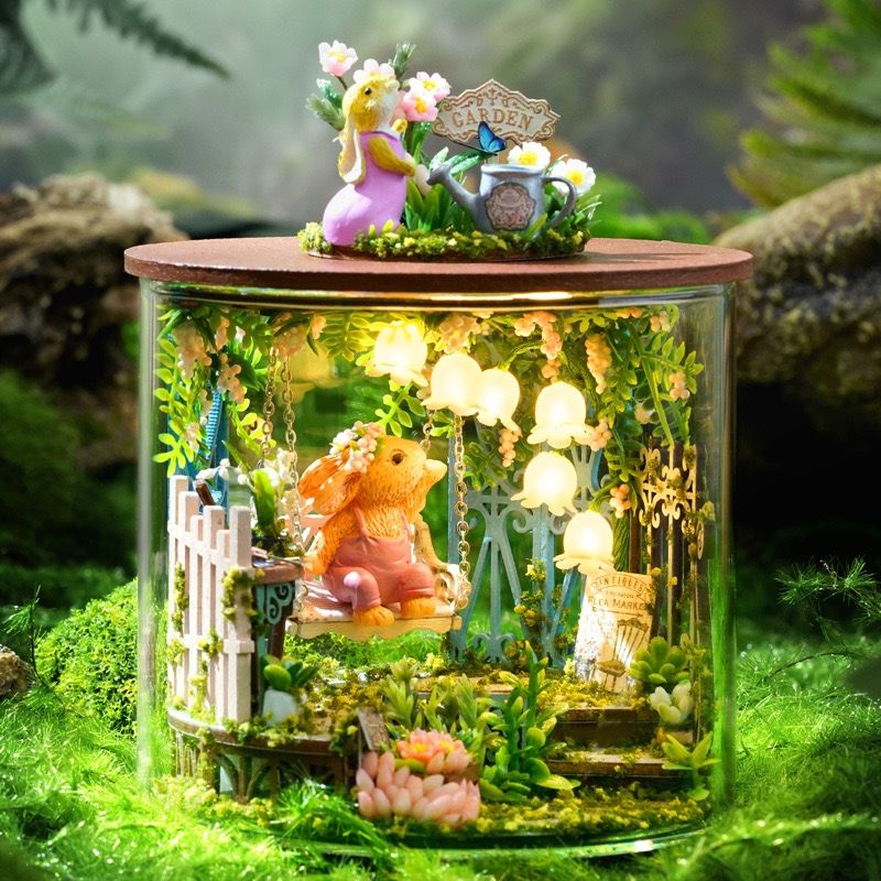image displaying an assembled Fairytale Garden DIY Miniature House Kit with lights on in a magic forest setting