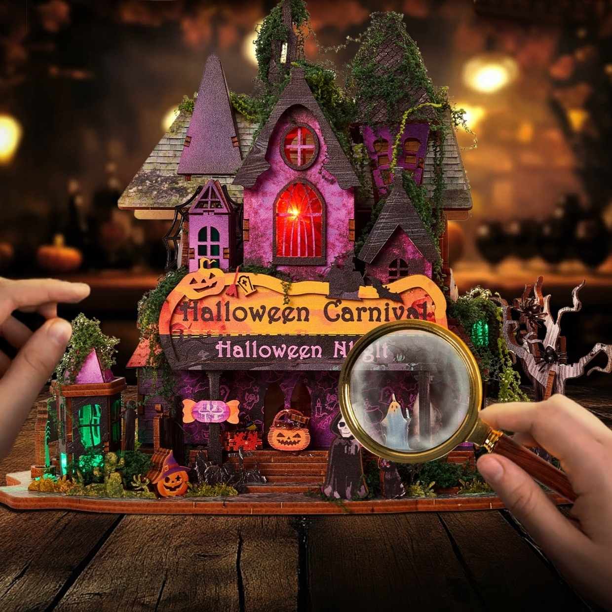 Halloween-themed miniature house with glowing lights and a magnifying glass held by a hand.