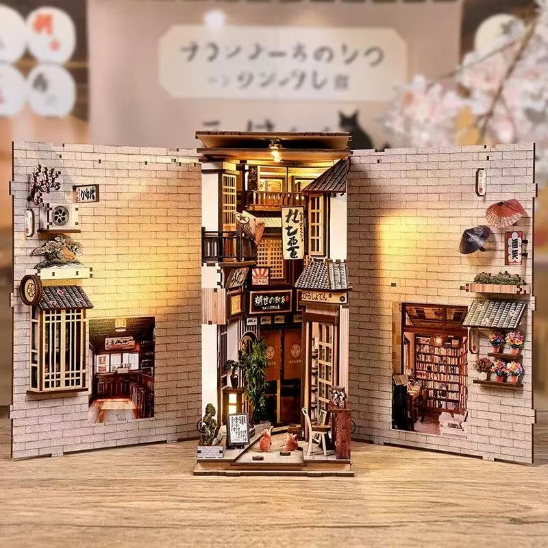spread out book nook model of a miniature Japanese alley with various items and a lit interior.