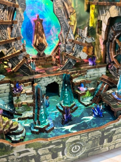 Detailed miniature diorama with stone architecture, water, and colorful lights.
