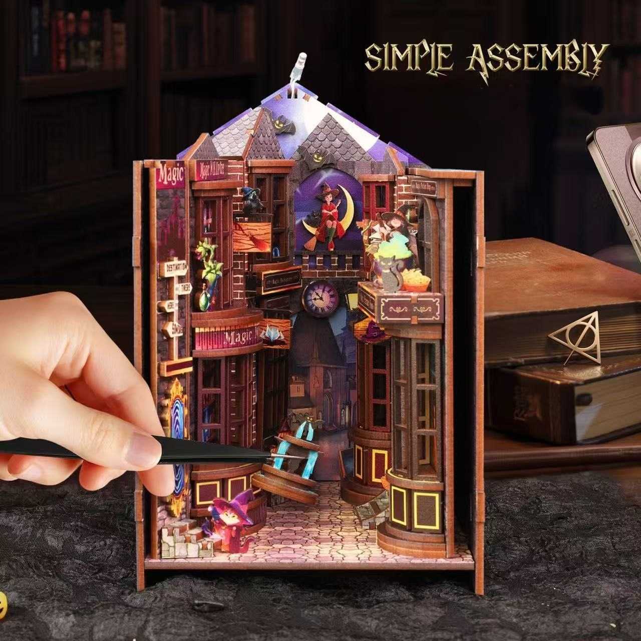 Hand assembling a book nook model of a magical building