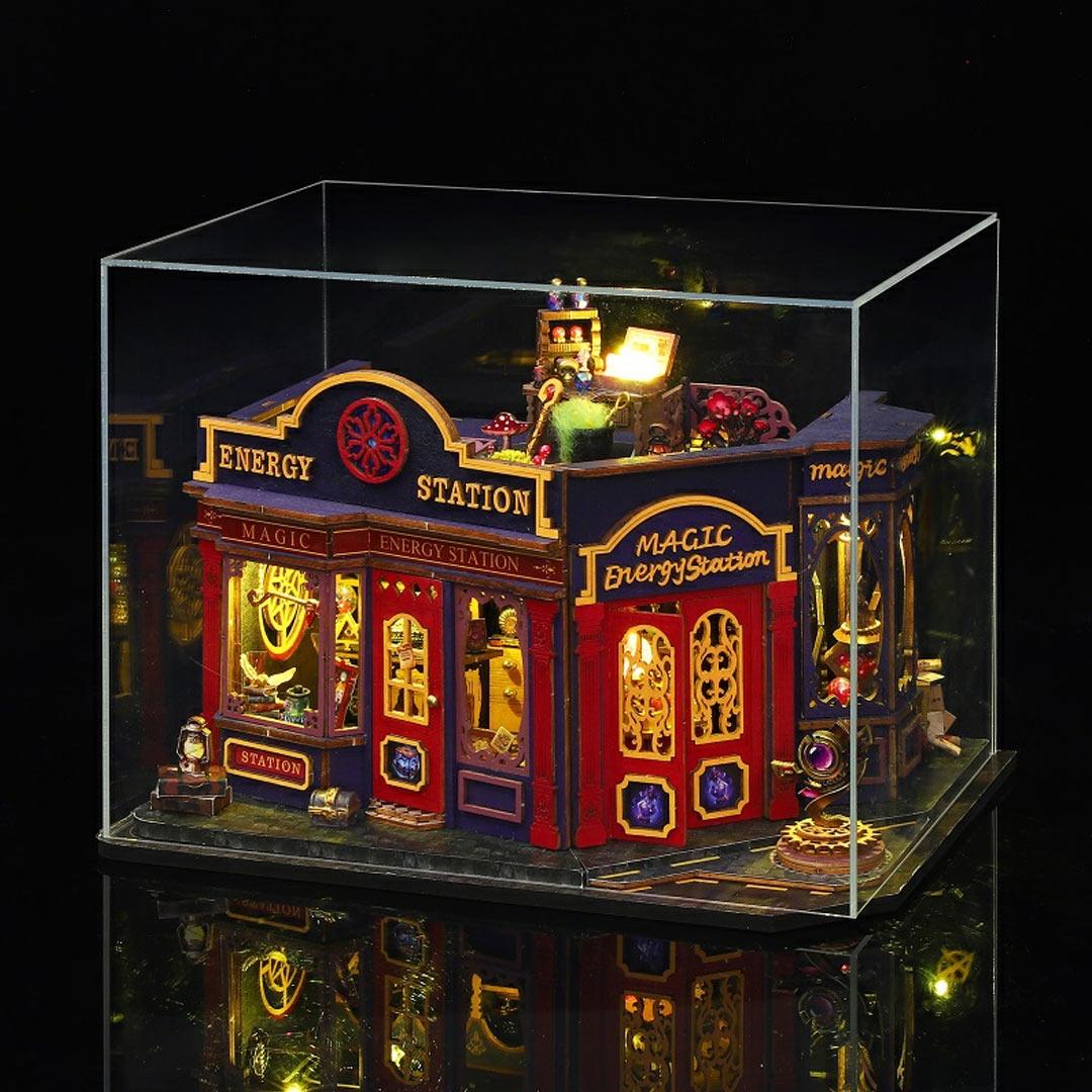 image displaying Magic Energy Station Dollhouse with lights on in a acrylic dust cover box