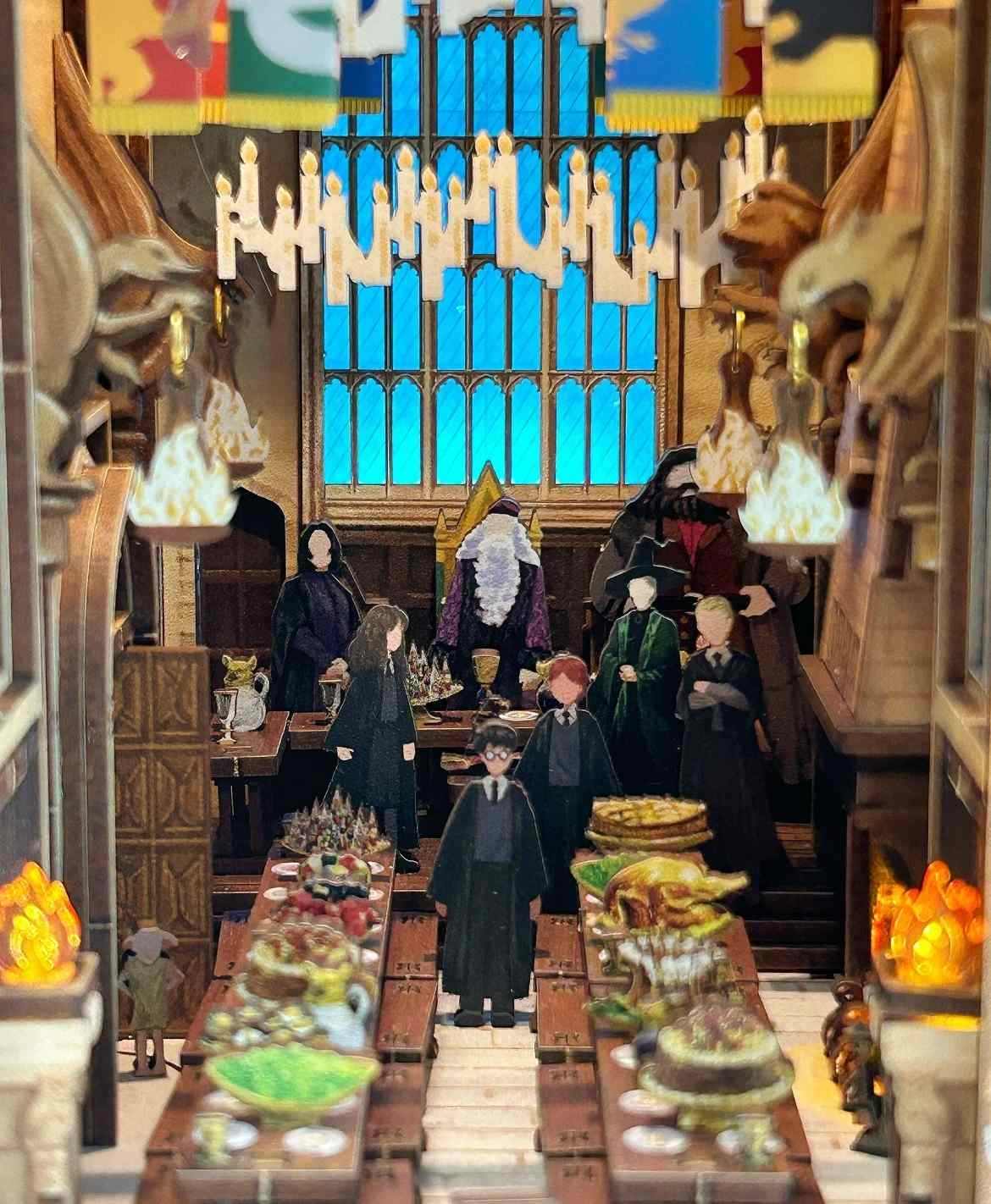 a miniature Hogwarts Great Hall with characters from a fantasy series, featuring a large window and detailed decor.