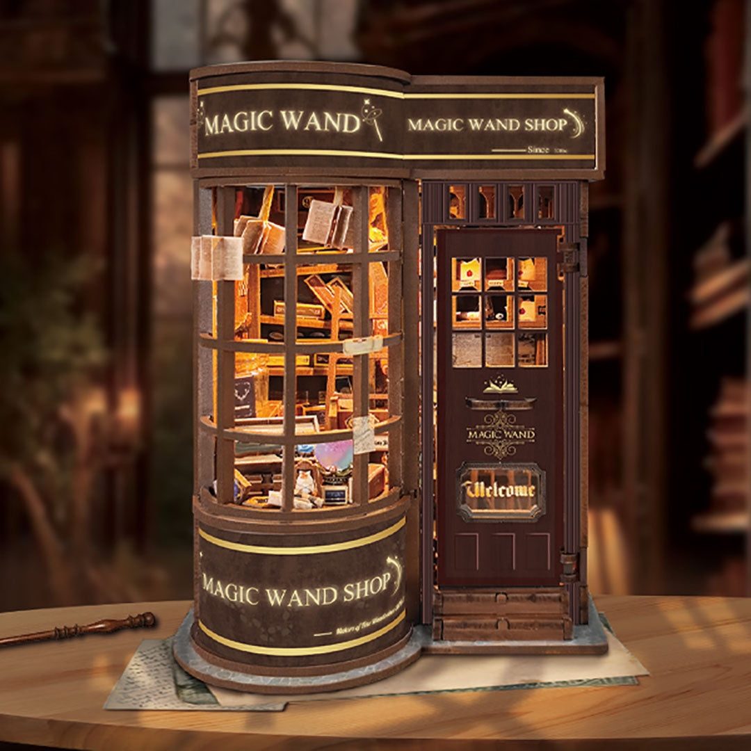 Model of a 'Magic Wand Shop' book nook with windows and wooden exterior on a wooden table