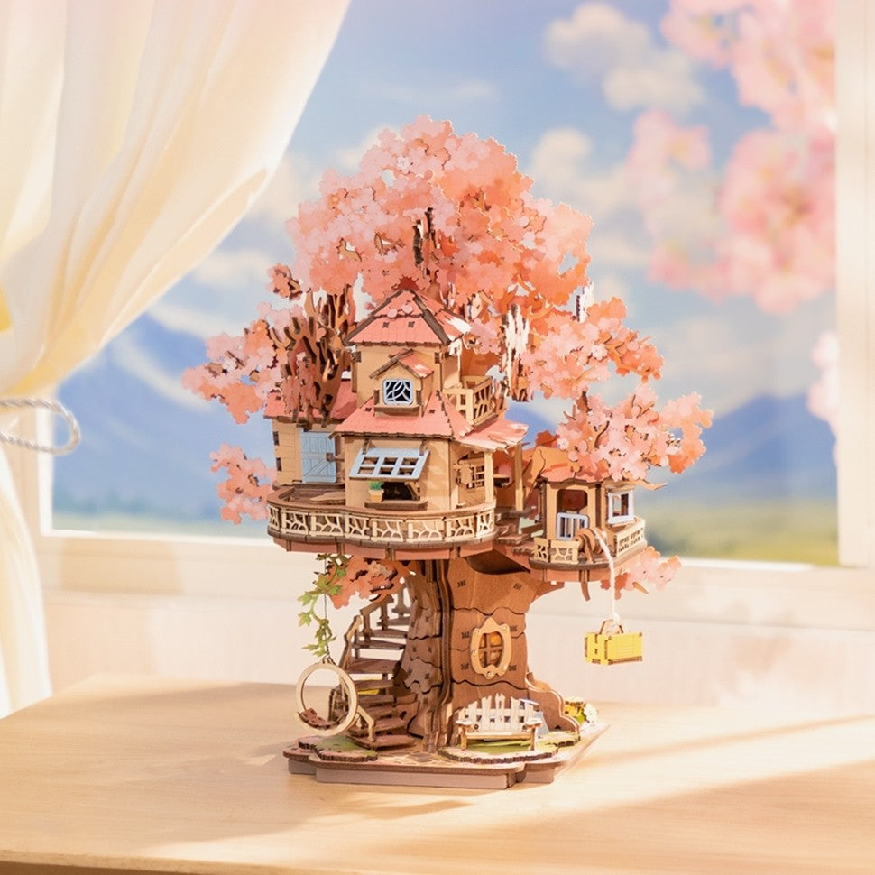 finished assembled Wooden puzzle model of a tree house with cherry blossom branches against a scenic background