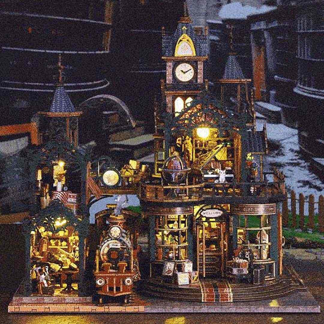 Detailed miniature house model of steampunk railway station, featuring
Victorian style architecture, with various lit-up elements at night