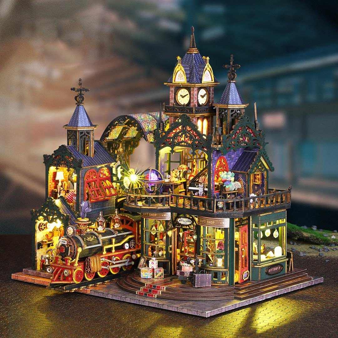 Detailed dollhouse model of a Victorian-style train station with lit-up features