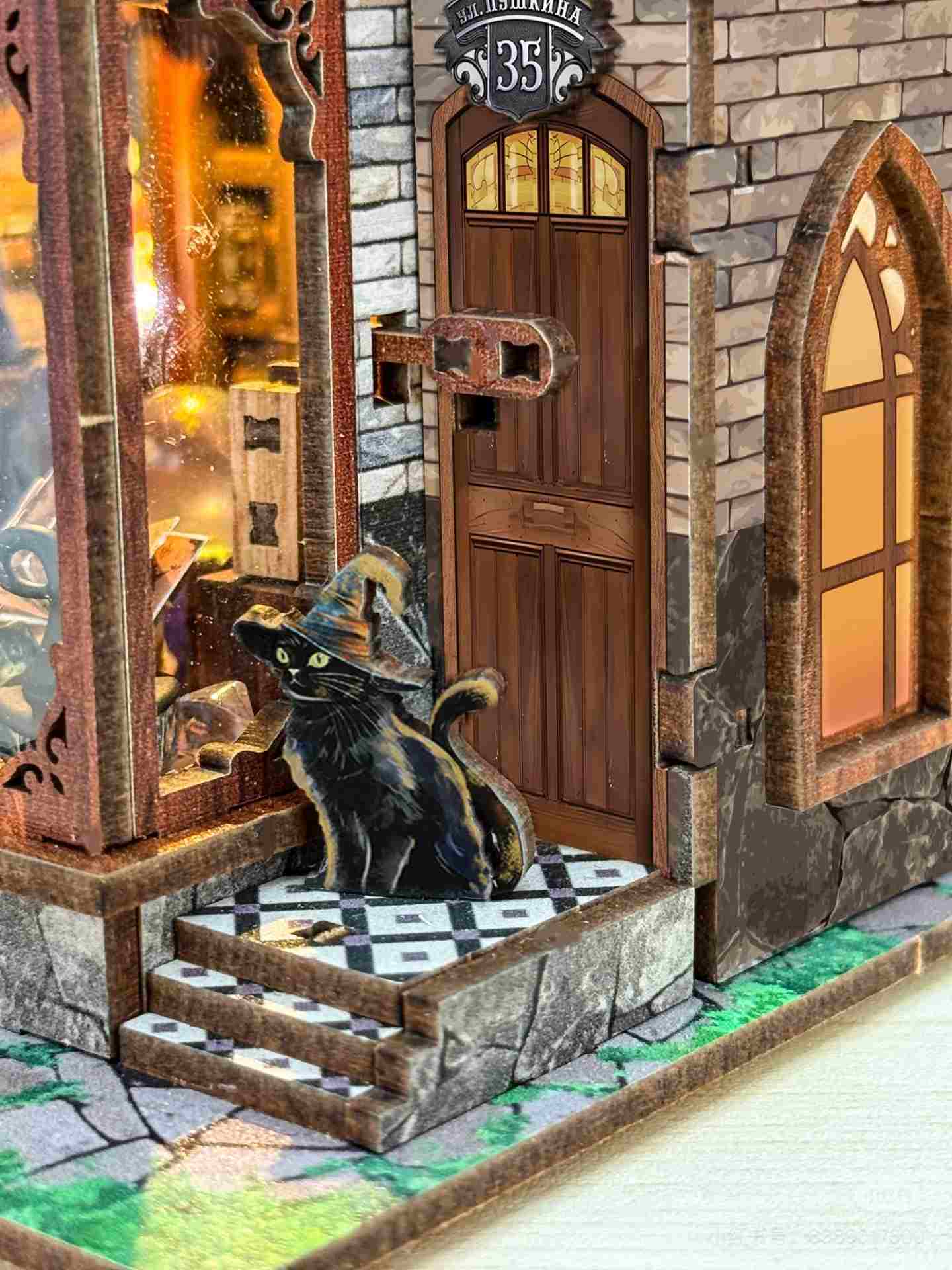 close up the miniature details of a stone building with a wooden door and a black cat on the steps