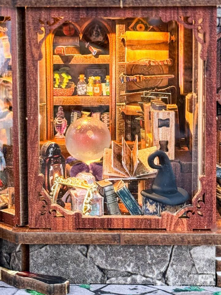 miniature Wooden cabinet with magical items including books, a globe, and potions.