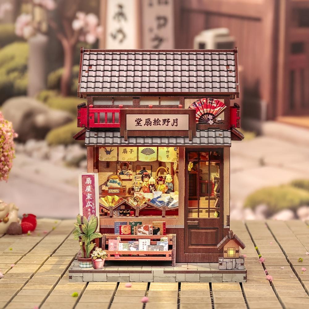 Miniature model of a traditional Japanese building with detailed architecture and decorative items on a wooden surface.