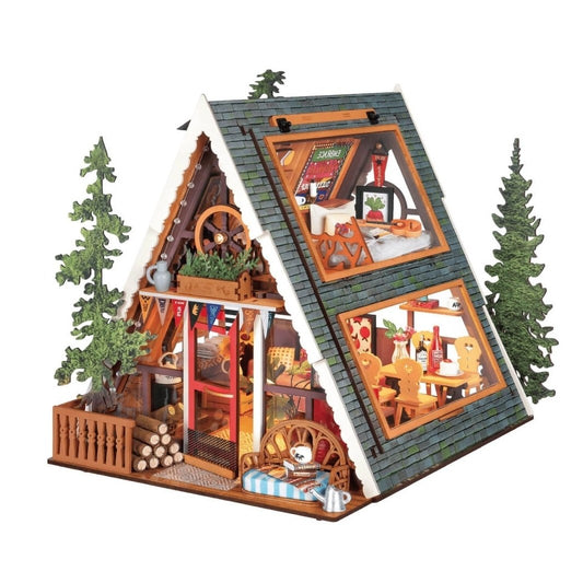 Wooden miniature model of a cabin with interior details and trees on a white background