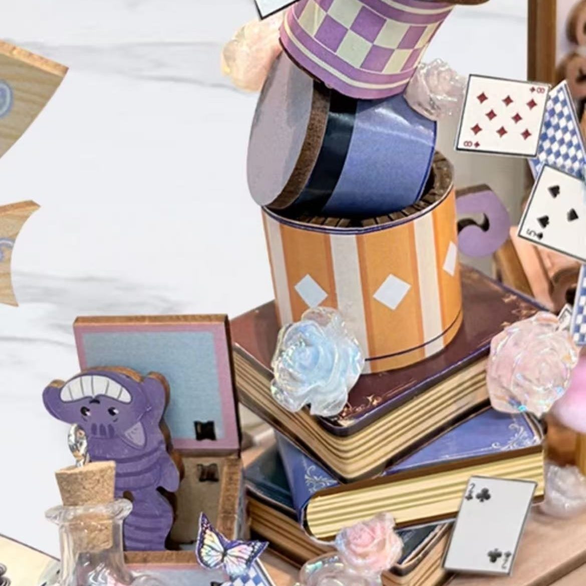 miniature items including a top hat, books, and playing cards on a white surface.