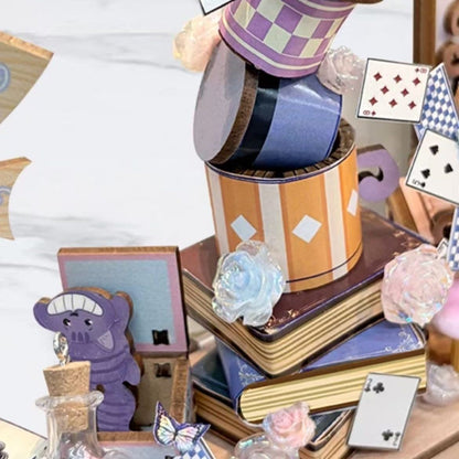 miniature items including a top hat, books, and playing cards on a white surface.
