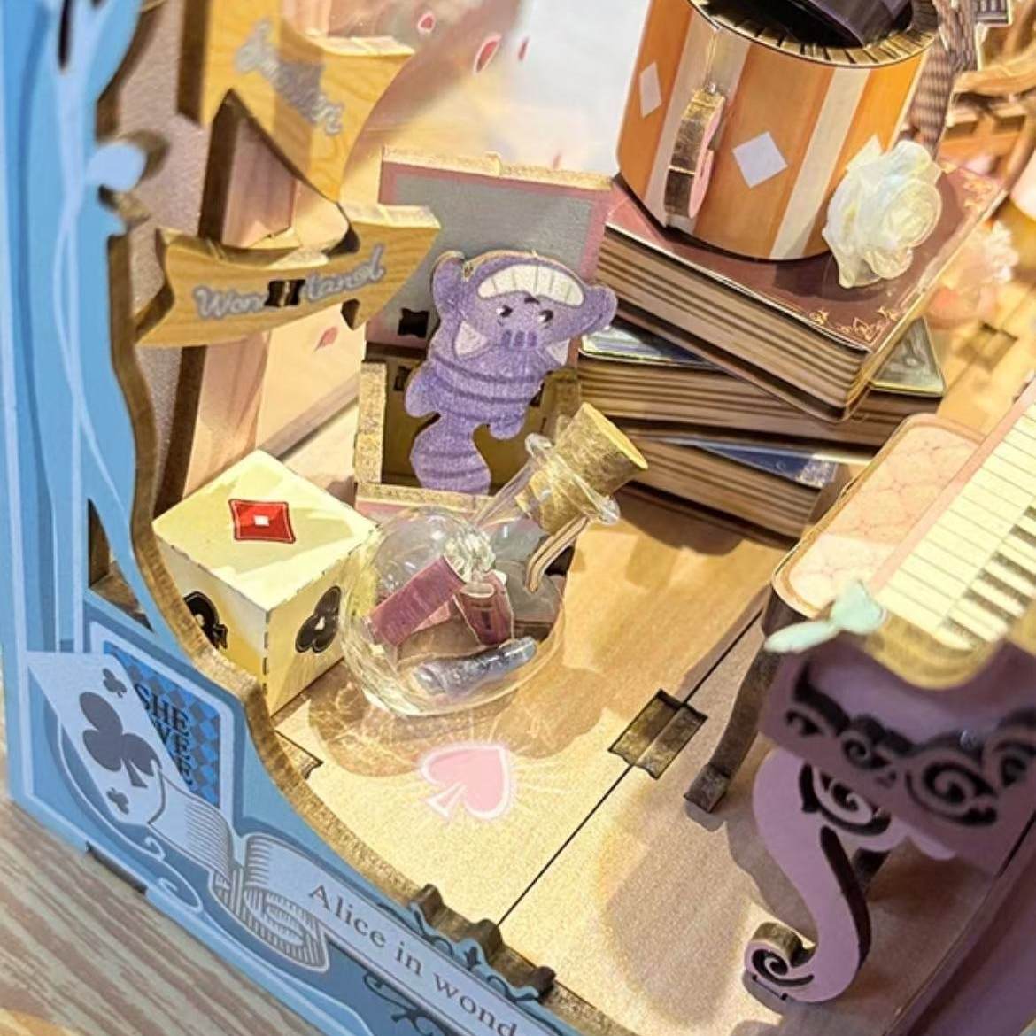 Detailed model of a scene from 'Alice in Wonderland' with a purple rabbit, books, and a castle.
