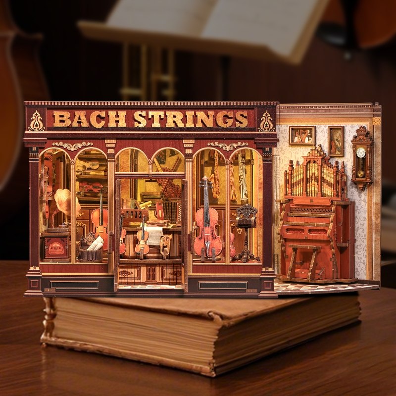 Miniature model of a music store named 'Bach Strings' with musical instruments on a wooden surface.