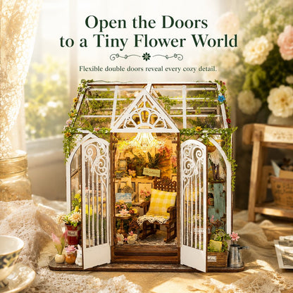 A miniature greenhouse dollhouse with white decorative double doors and a cozy floral interior, displayed on a lace-covered surface with decorative props and text reading 'Open the Doors to a Tiny Flower World.'.