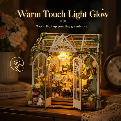 A miniature greenhouse craft with glowing warm lights, displayed on a wooden table in a cozy room setting. The text 'Warm Touch Light Glow' and 'Tap to light up your tiny greenhouse.