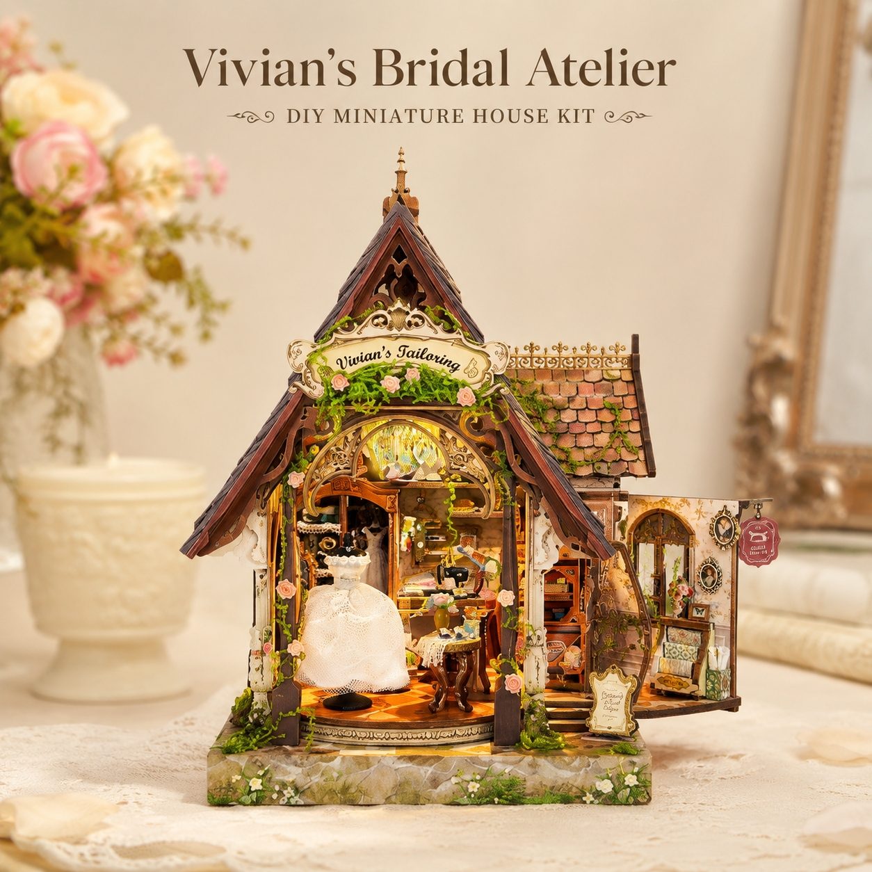 A decorative DIY miniature house kit labeled 'Vivian's Bridal Atelier' displayed on a tabletop. The tiny shop structure has a dark brown gabled roof, warm amber interior lighting, floral greenery, and miniature details including a white bridal gown display and shop fixtures.