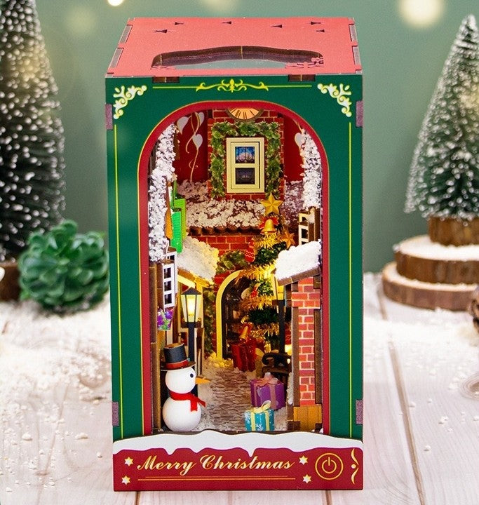 image displaying front side view of the assembled Christmas Winter DIY Book Nook kit in a Christmas-themed table setting