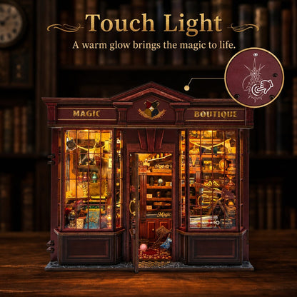 A decorative miniature shop display labeled 'MAGIC BOUTIQUE' with warm glowing interior lights, shown on a wooden surface against a dark bookshelf background. Text at the top reads 'Touch Light' and 'A warm glow brings the magic to life.