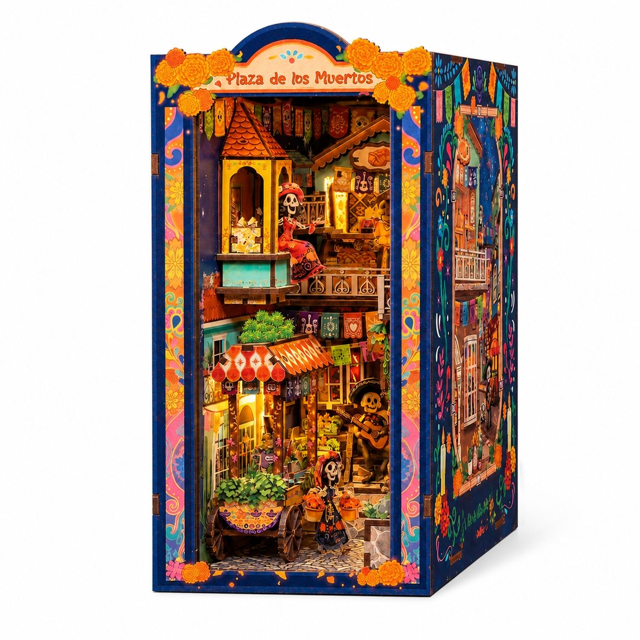 A colorful miniature Dia de los Muertos (Day of the Dead) city book nook model titled 'Plaza de los Muertos', featuring a detailed multi-story street scene with skeleton characters, orange marigolds, and traditional Mexican architecture, shown on a clean white background.