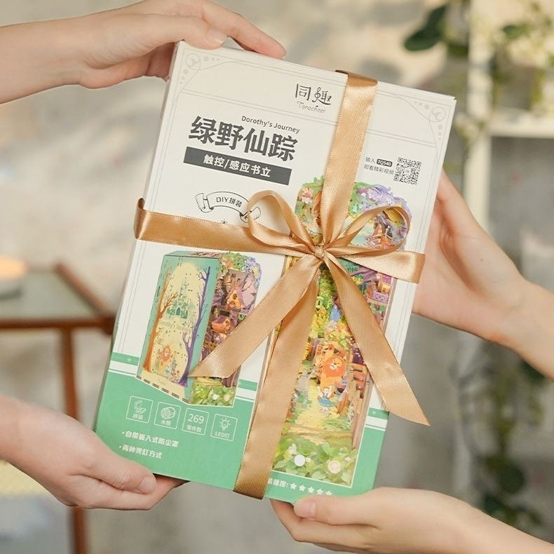 Two hands exchanging a Dorothy's Journey packed with a decorative ribbon against a blurred indoor background