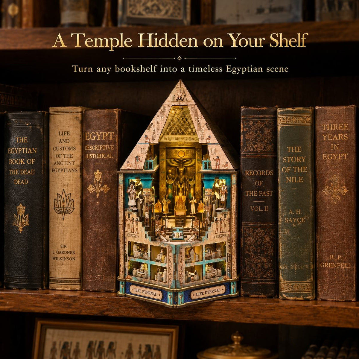 A decorative miniature temple display set on a wooden bookshelf between vintage books. The central product is a detailed multi-level golden and blue temple model with a pointed roof and small illustrated panels.