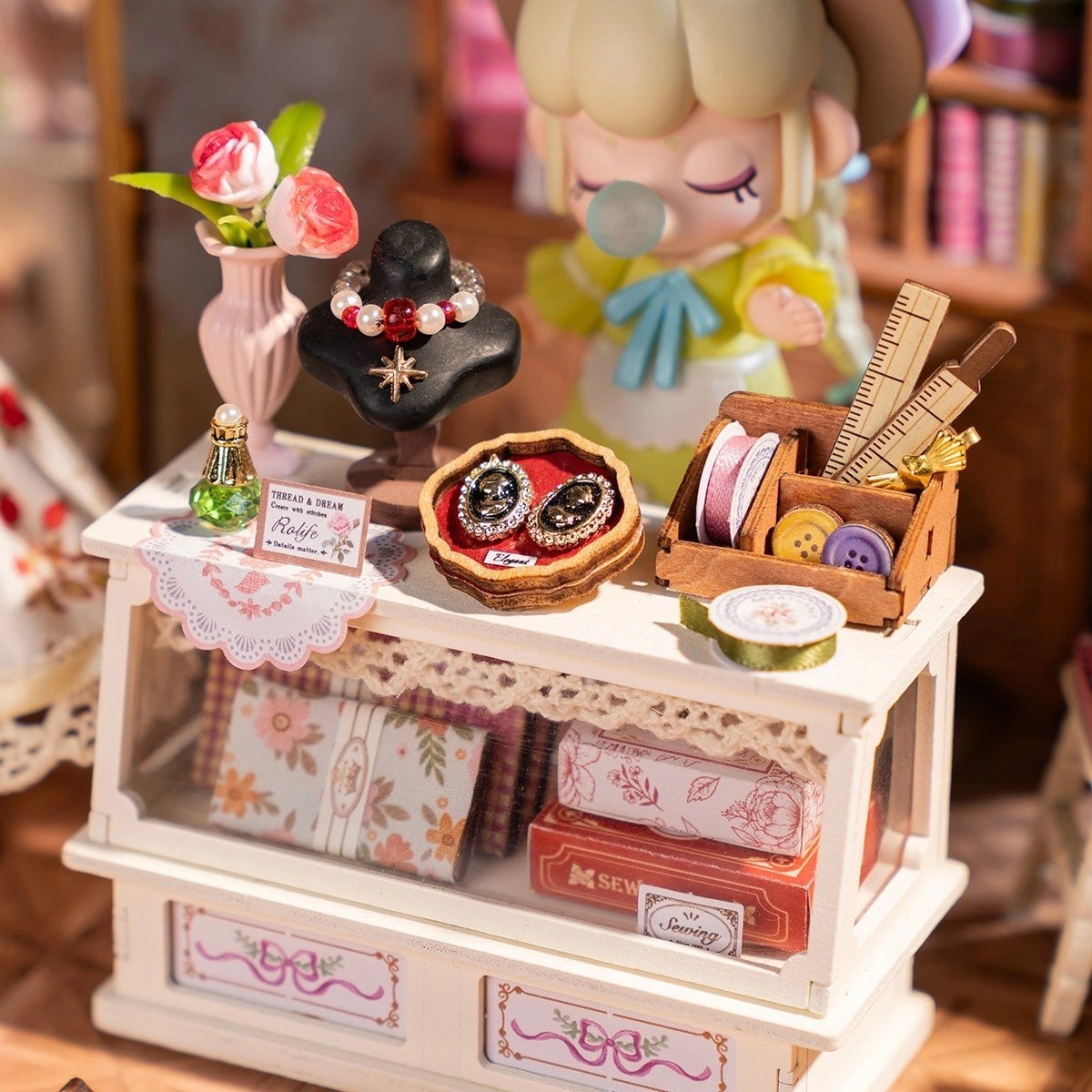 Miniature sewing kit on a wooden stand with various sewing supplies.