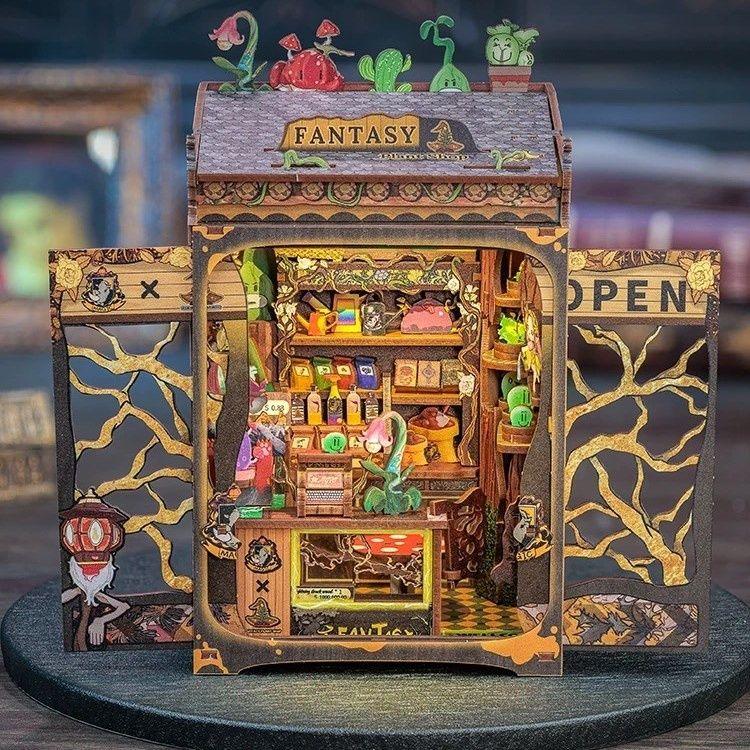 Fantasy Plant Shop DIY Book Nook Kit, a mystical miniature shop filled with magical plants, complete with a touch-activated light and protective dust cover. Perfect for any book lover’s collection. Perfect for those who love the whimsical world, DIY enthusiasts, bookend lovers, model building lovers, dollhouse collectors, bookshelf insert decor.