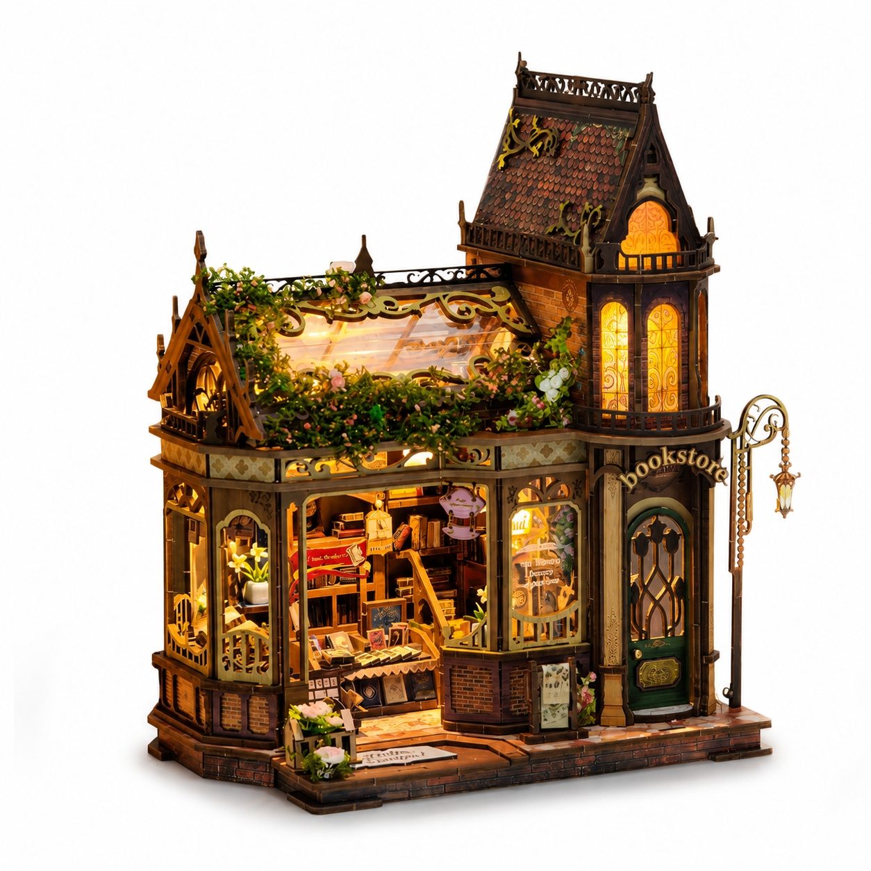 A miniature fantasy bookshop dollhouse with intricate architectural details, warm glowing interior lights, and a decorative street lamp, shown on a plain white background.