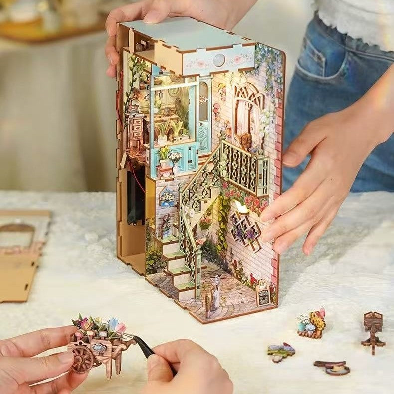 Puzzle model of a miniature house with detailed interior and decorative elements, held by hands on a light surface.