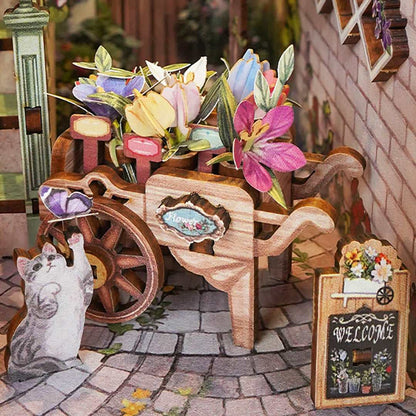 Miniature wooden cart with flowers and a cat figurine on a decorative setting