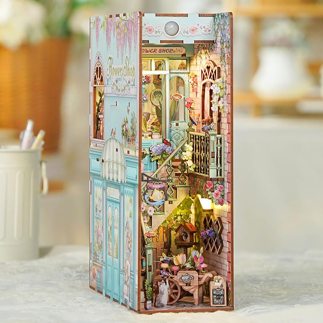 wooden book nook of a flower shop dollhouse with floral and architectural details.
