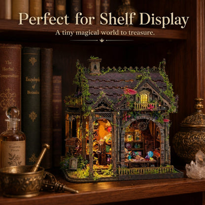 A miniature fairy-tale house display with glowing warm interior lights, set on a wooden shelf among books and decorative objects. Text at the top reads 'Perfect for Shelf Display' and 'A tiny magical world to treasure.