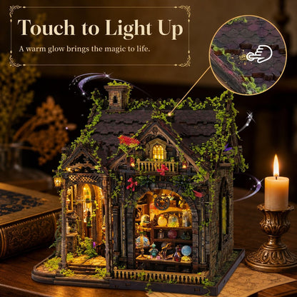 A decorative miniature house model with a dark gray roof, green ivy details, and warm glowing interior lights, shown on a wooden surface with a lit candle and an inset showing the touch-sensitive light-up feature.