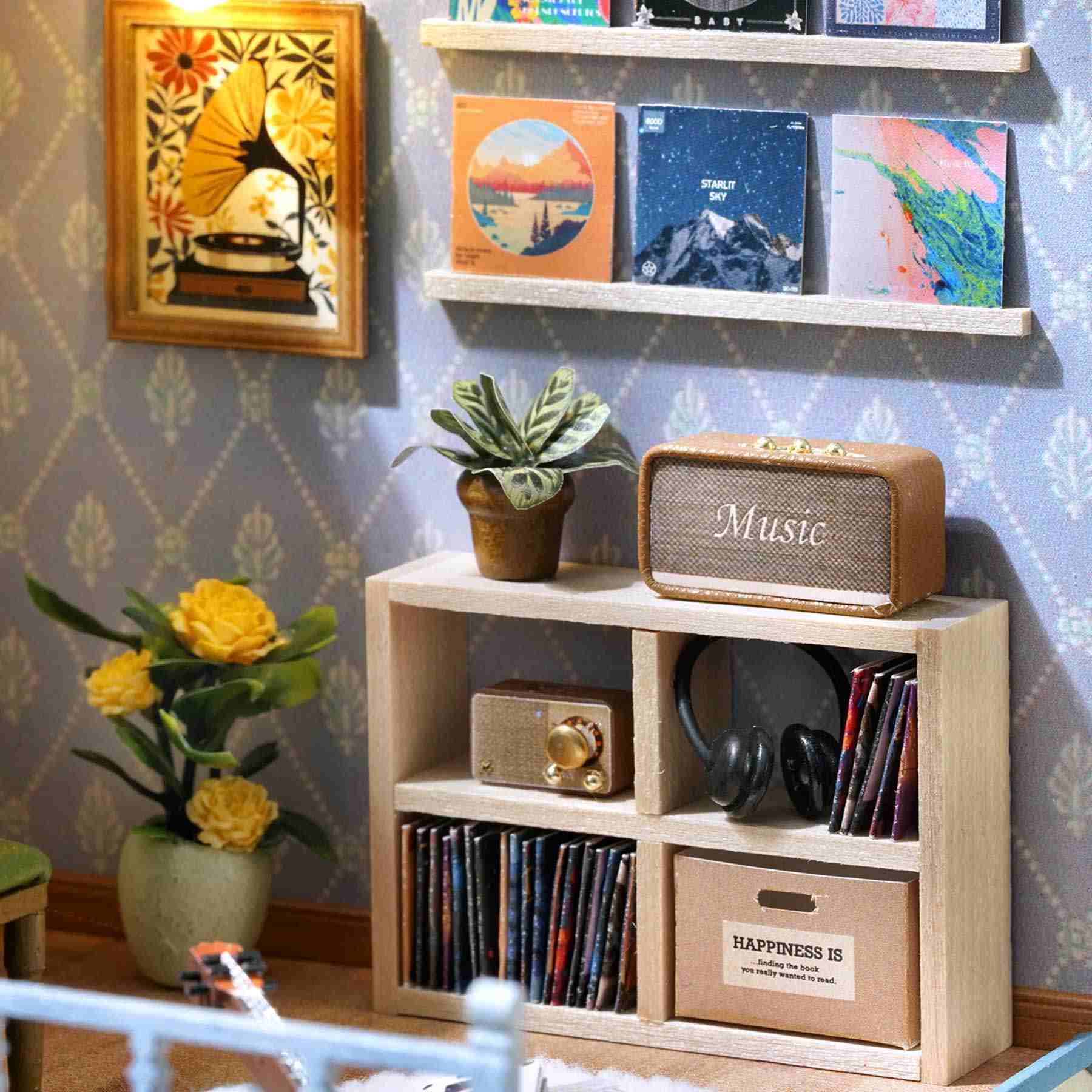 Wooden miniature shelf with decorative items including a radio, speakers, and books against a patterned wall.