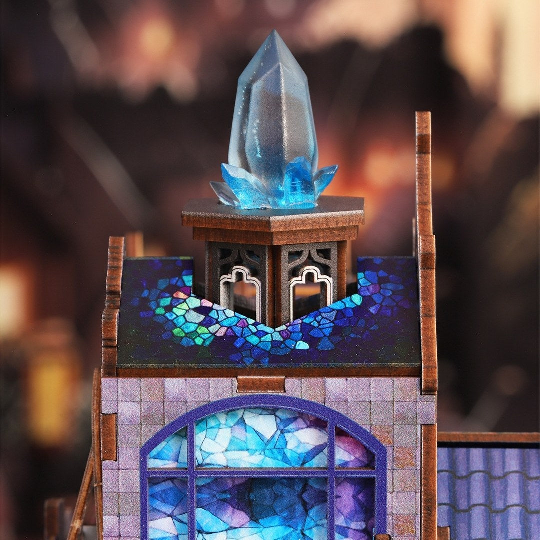 Decorative miniature house model of a building with stained glass windows and a crystal on top against a blurred background