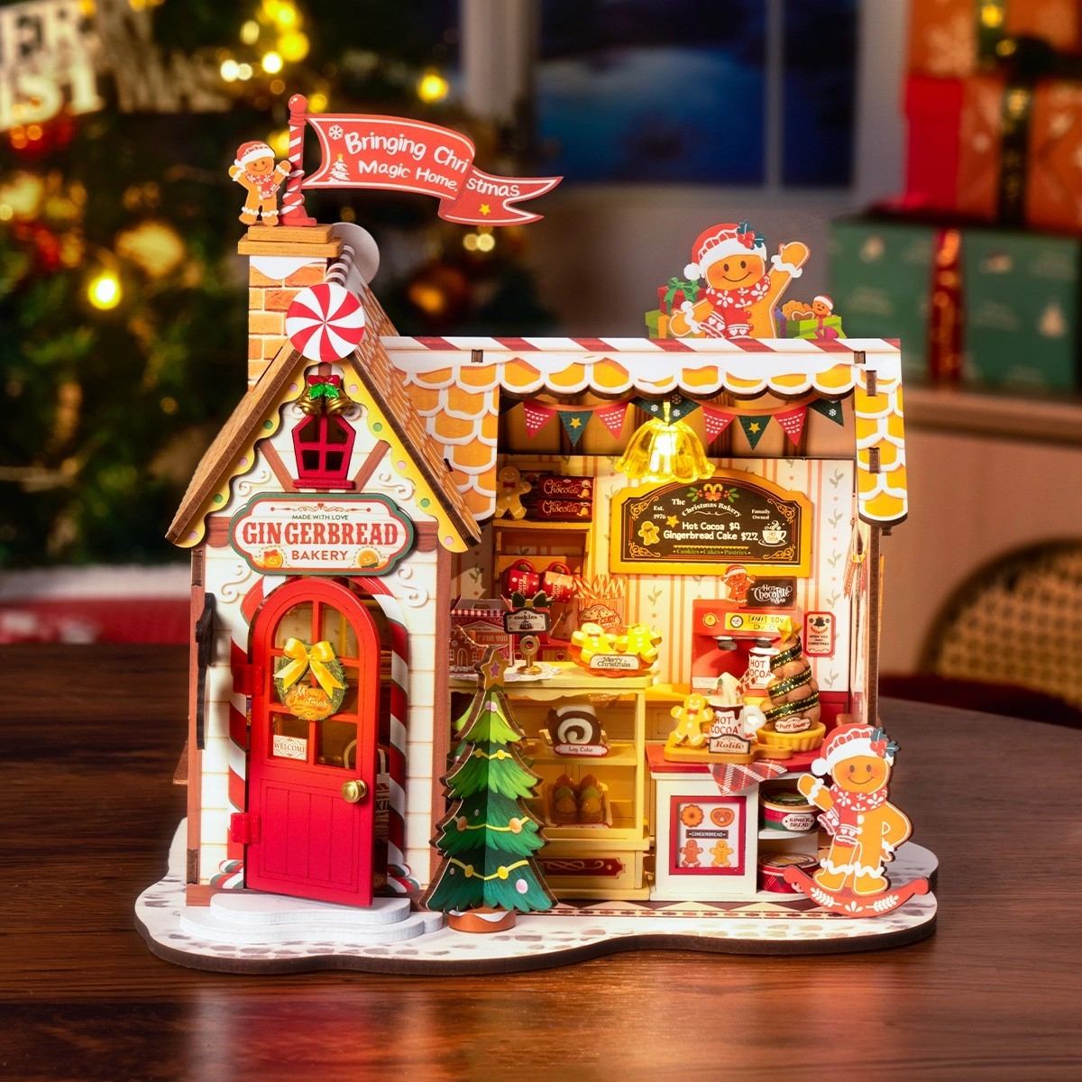 Gingerbread bakery miniature model with interior lights on a wooden surface, Christmas tree in the background