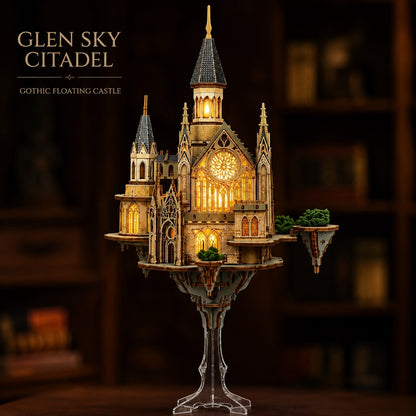 A 3D wooden model of the Glen Sky Citadel, a floating gothic castle, displayed on a clear acrylic stand against a dark, blurred library background. The model features warm yellow glowing windows and a detailed stone facade.