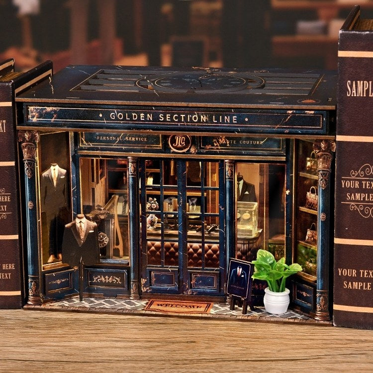 tailor shop themed miniature house between books resembling a store front, surrounded by actual books.