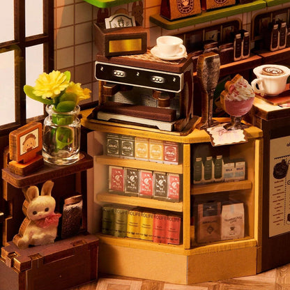 Miniature coffee shop setup with a coffee machine, cups, and decorative items.