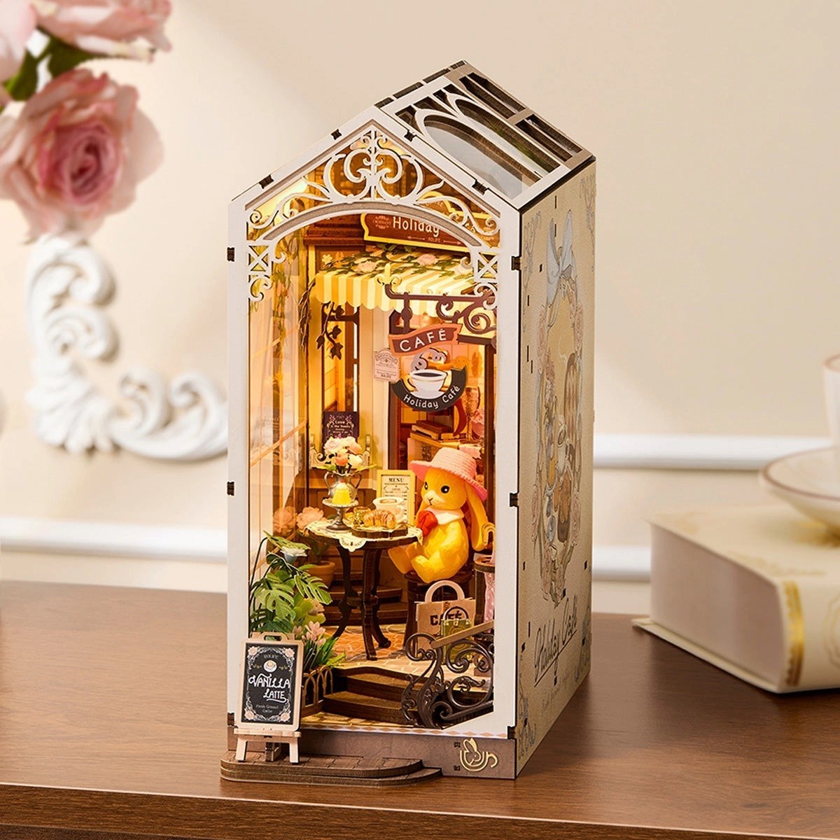 Miniature book nook model of a cafe scene inside a decorative box on a wooden surface.