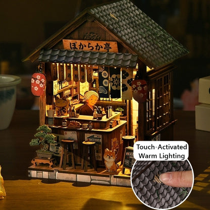 Wooden miniature model of a Japanese restaurant with warm lighting and detailed interior.