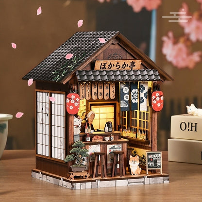 Wooden book nook model of a Japanese-style building with cherry blossoms in the background